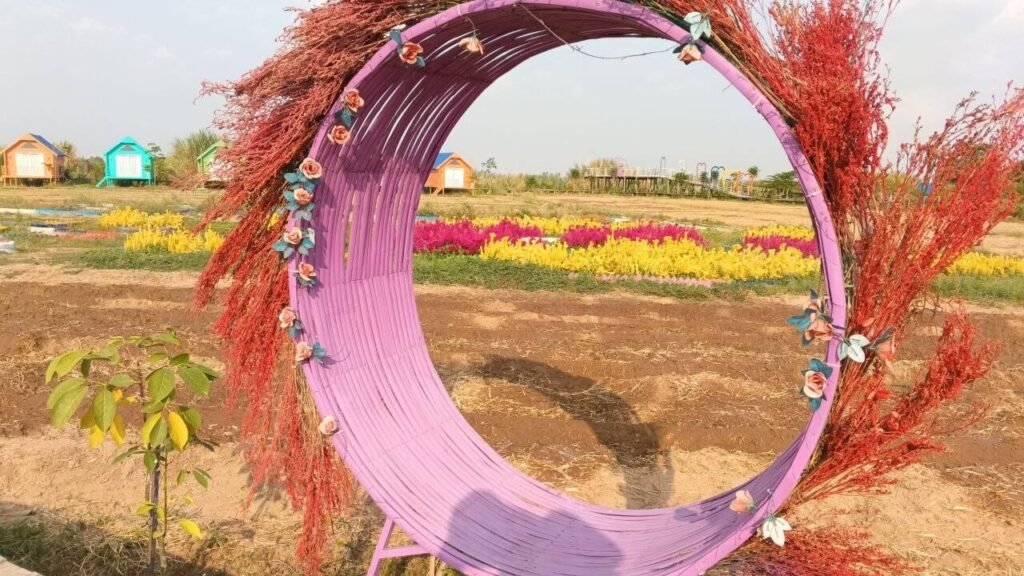 Close up of a circular metal garden arch wrapped in bright purple painted bamboo strips and rustic dried red branches.