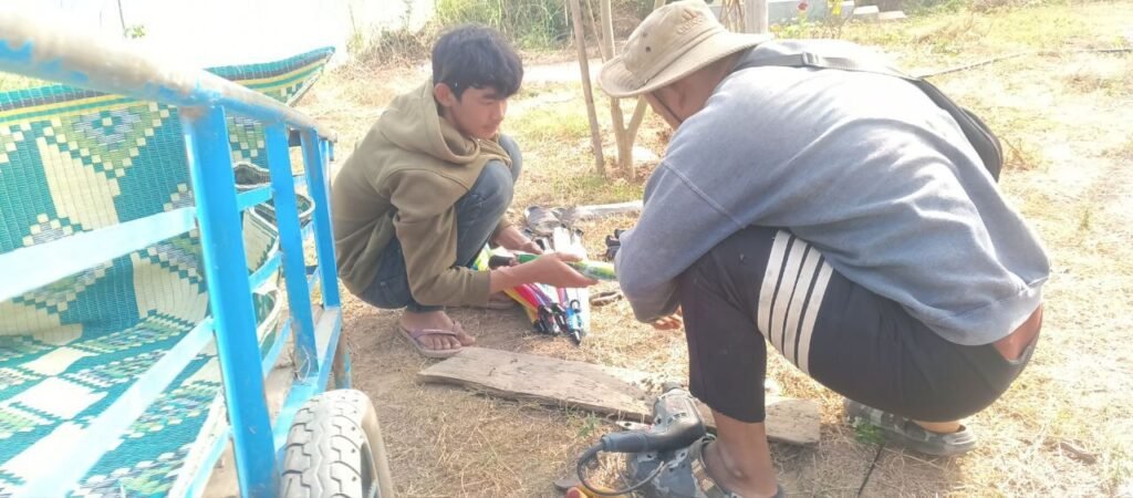 Two people working on the ground in a garden field, assembling and bending materials for a DIY rebar garden arch without heavy machinery.