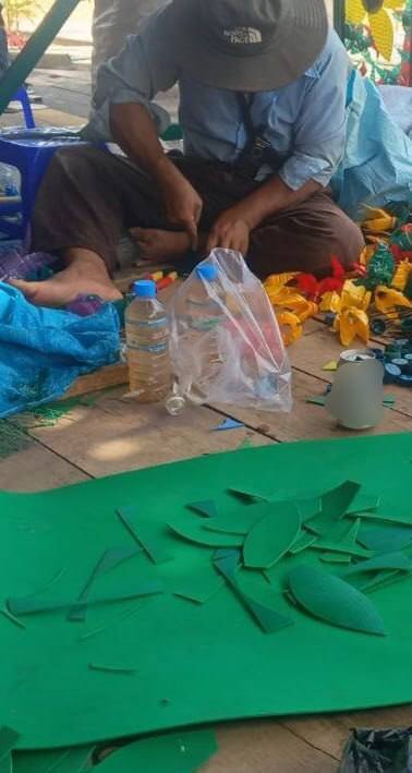 Hand-cutting green leaves from upcycled rubber sheets for garden decor.