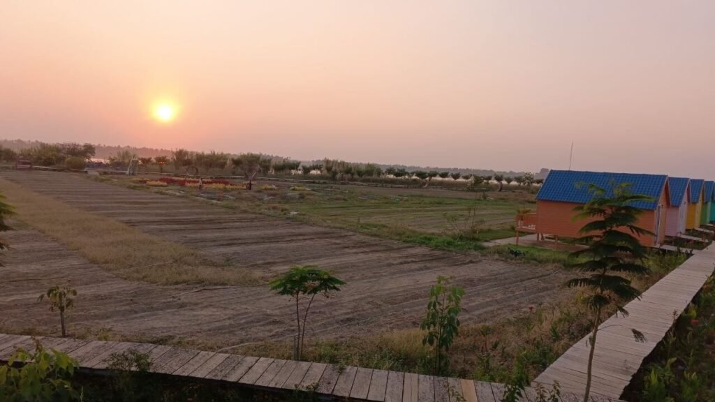 A row of colorful relaxation cottages at Dream Garden with unplanted soil in the foreground during early development.
