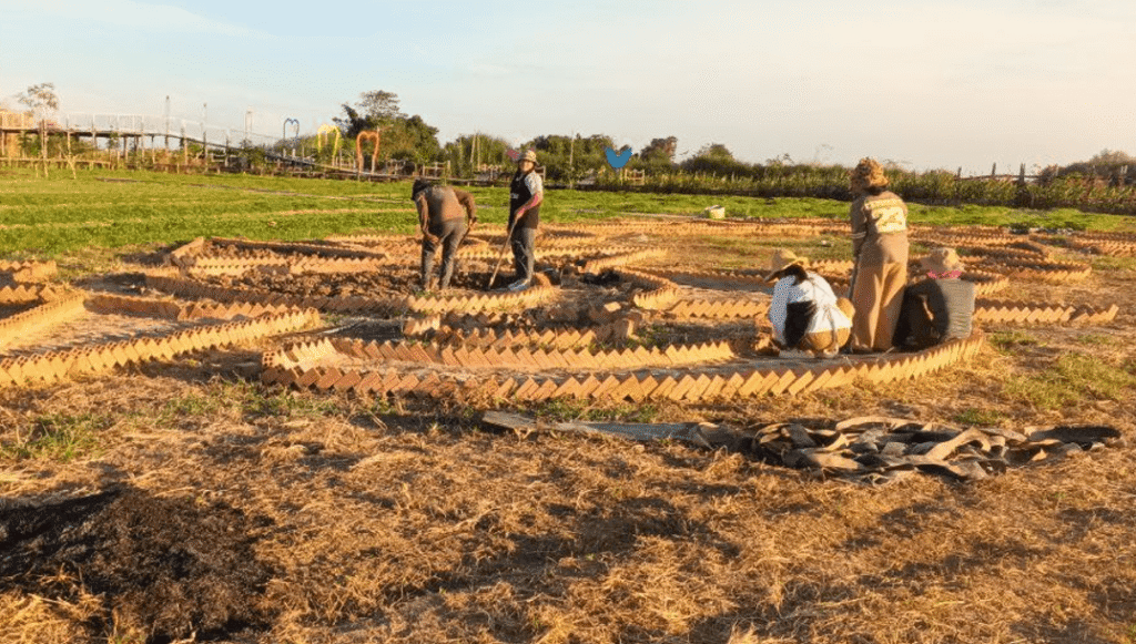 A team of garden workers collaborating to build intricate brick hardscaping paths in an empty dirt field.