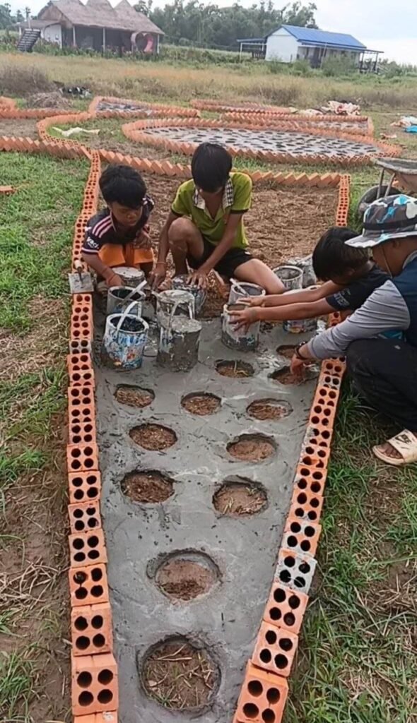 A group of people crouching and pressing white paint buckets into wet grey concrete mix within a brick formwork.