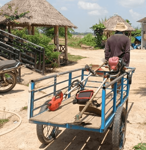 A blue metal cart carrying a red brush cutter, used for early landscaping jobs.