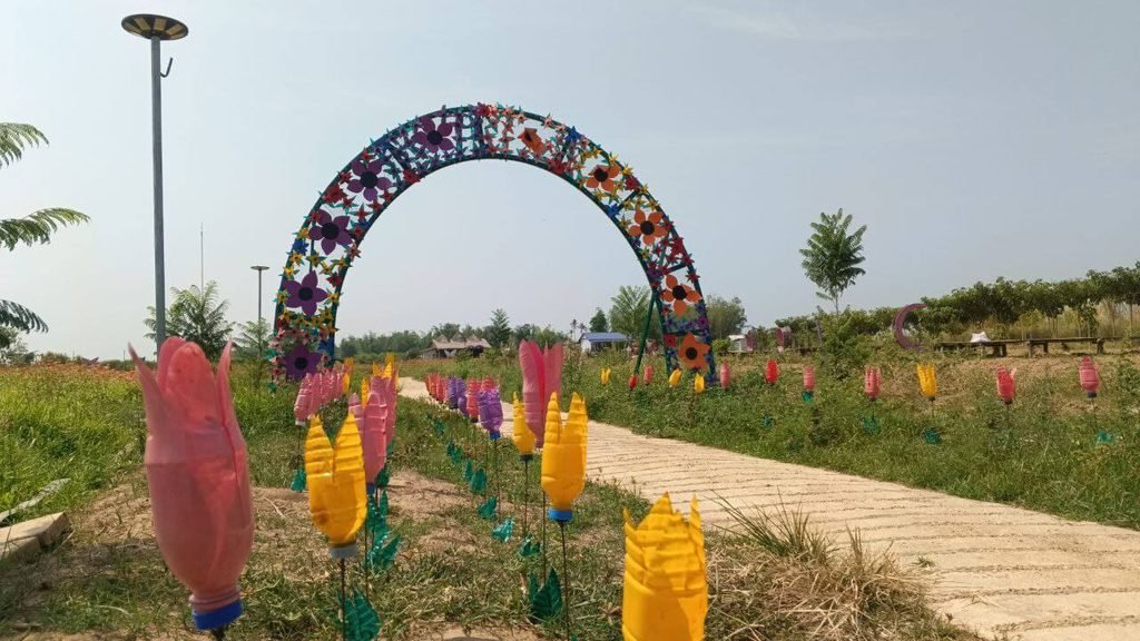 A garden pathway lined with artificial tulip flowers made from colorful recycled plastic bottles.