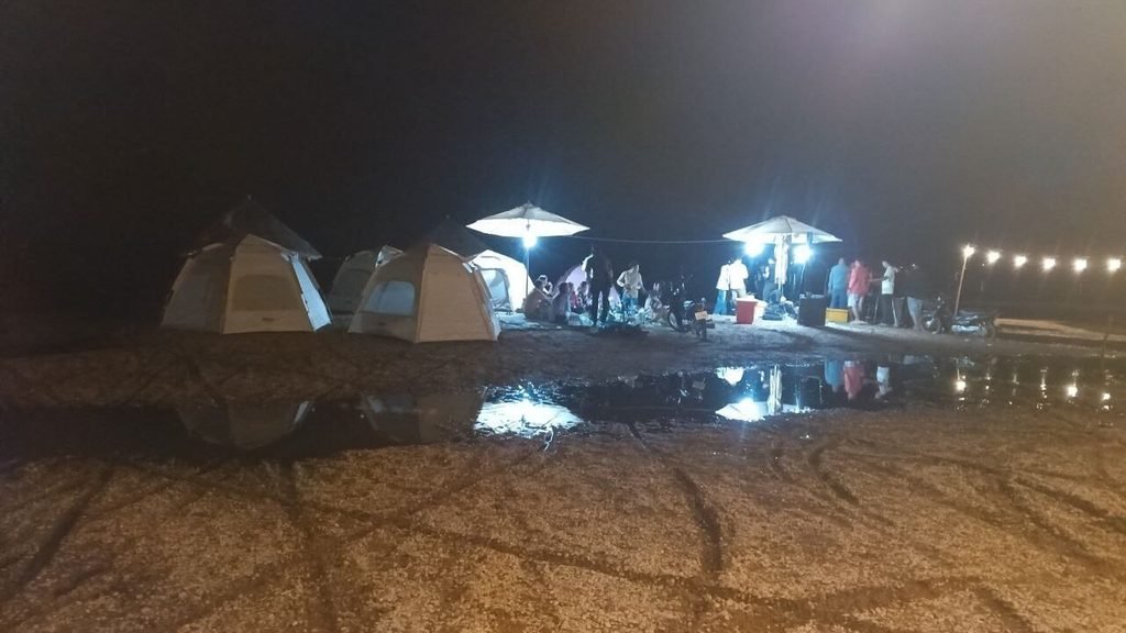 Large puddles of water and mud pooling around canvas glamping tents during the rainy season.